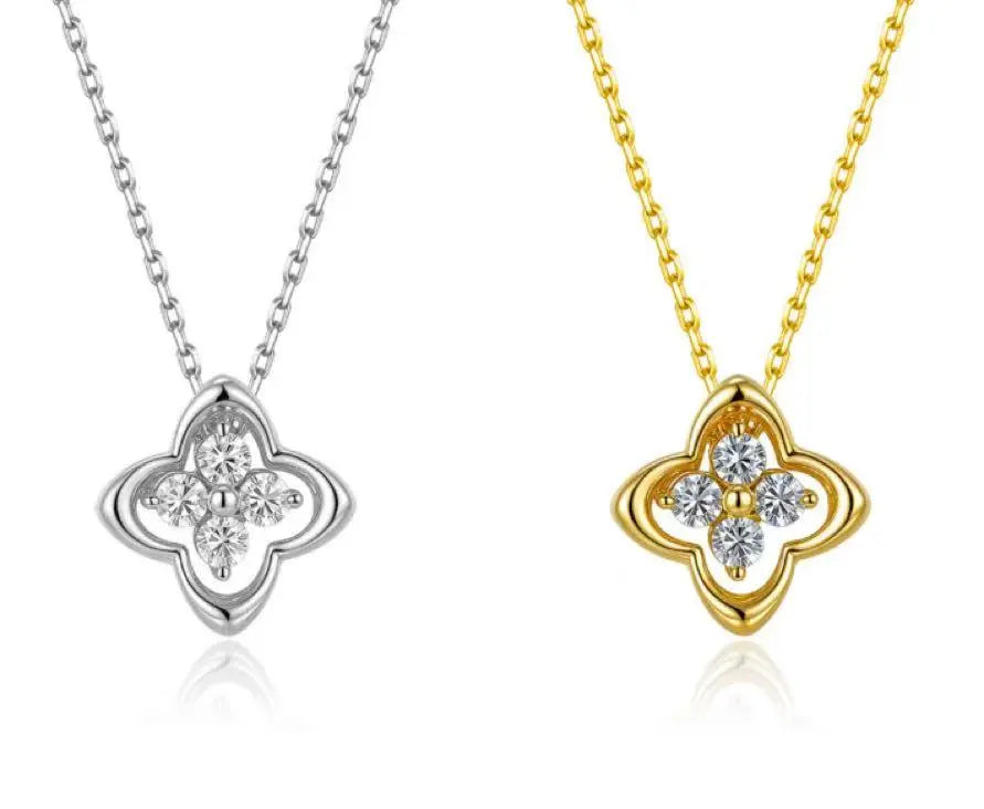 Two clover-shaped pendants, one gold and one silver, on white backgrounds.