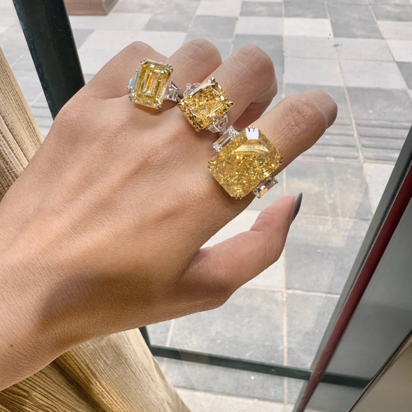 Hand wearing three yellow diamond rings with a blurred background