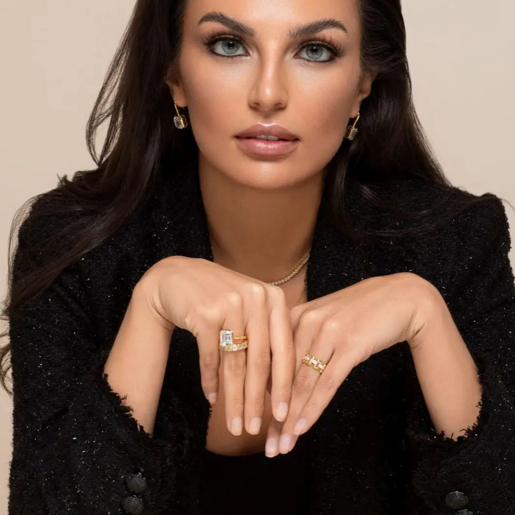 Woman wearing a black outfit with jewelry against a beige background