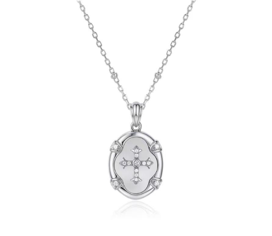 Silver necklace with a pendant featuring a cross design on a white background