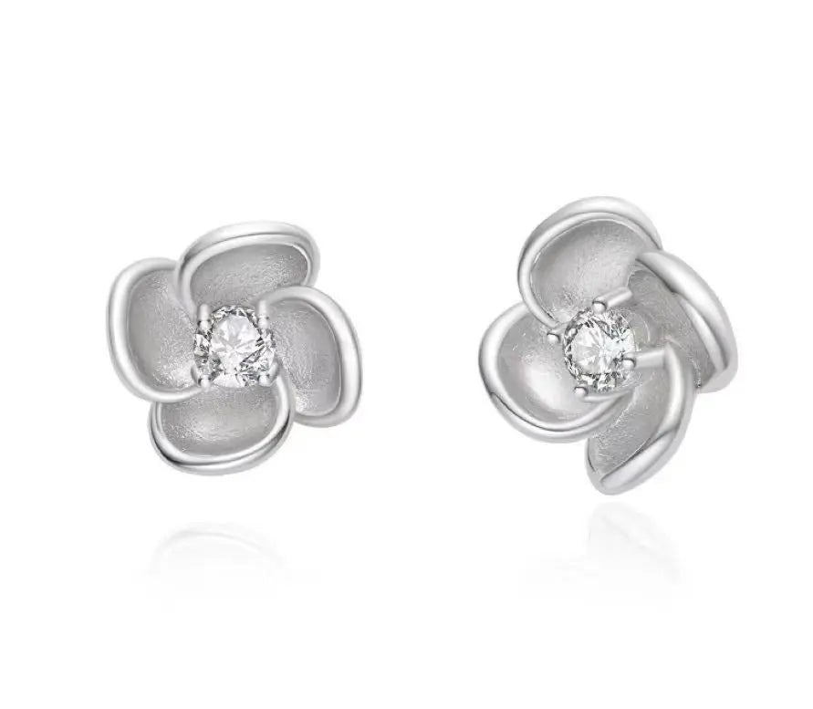 Silver flower-shaped earrings with clear gemstones on a white background