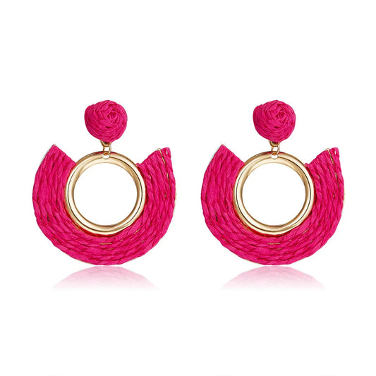 Fuchsia pink half-moon woven earrings with central gold ring.