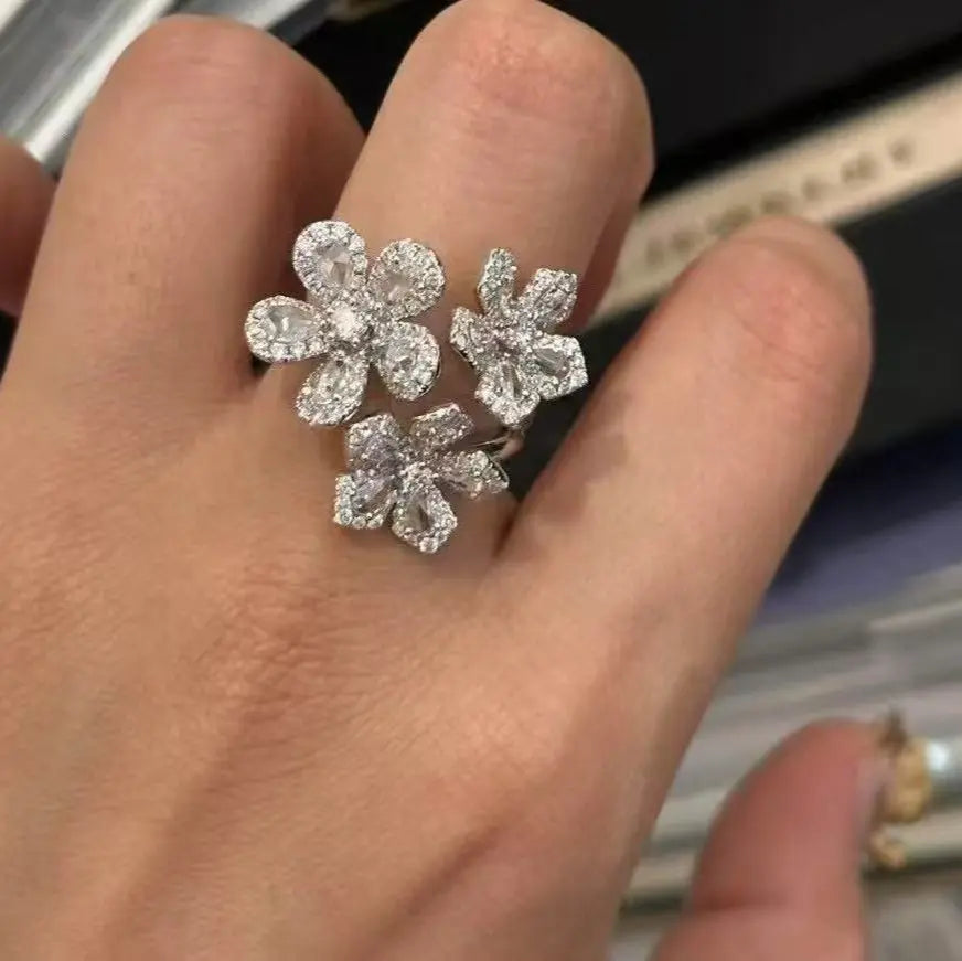 Diamond flower-shaped earrings on a hand with a blurred background