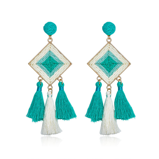 Turquoise and white woven diamond-shaped earrings with tassels.