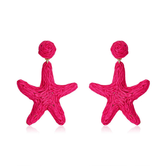 Bright hot pink starfish-shaped earrings made from woven fibers, called Coral Star Drops.