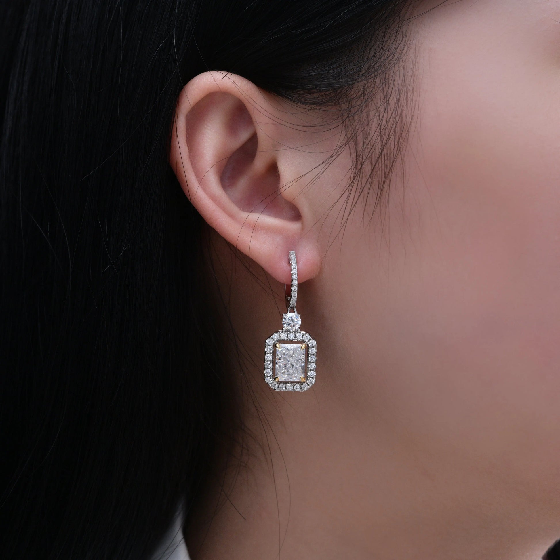 Anna Zuckerman Harper Radiant Huggies in White Diamond featuring radiant cut center stone with halo setting on sterling silver. Elegant 1-inch drop earrings for women.