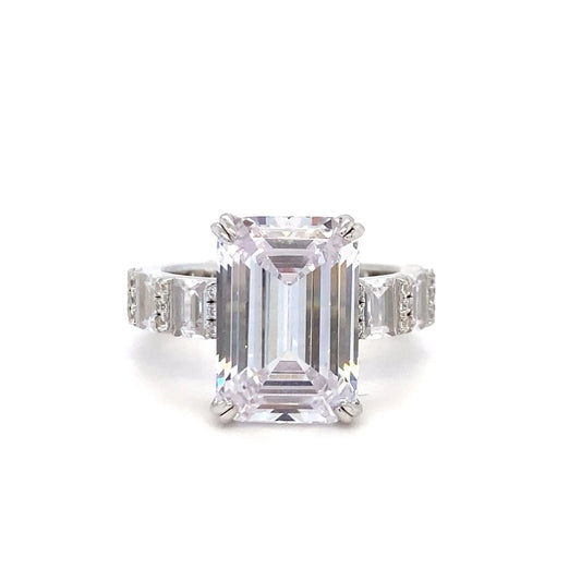 Diamond ring with emerald-cut center stone on a white background
