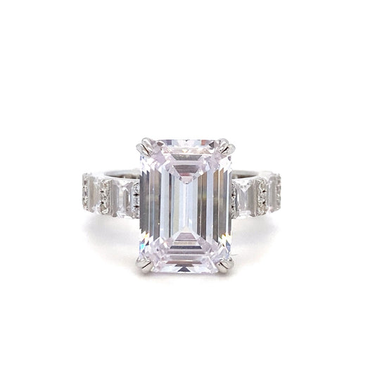 Diamond ring with emerald-cut center stone on a white background