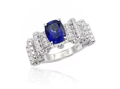Silver ring with a blue gemstone and diamond-like stones on a white background