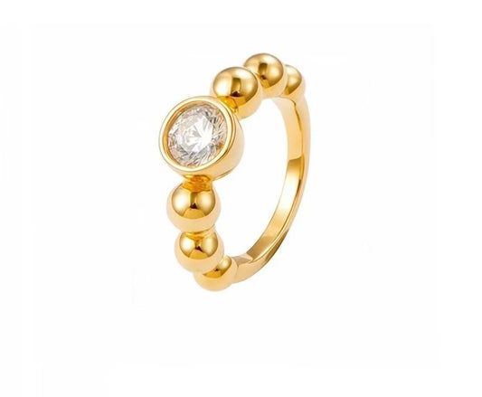 Gold ring with a central diamond and three smaller beads on a white background