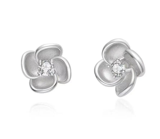 Silver flower-shaped earrings with clear gemstones on a white background
